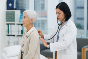 Elderly woman receiving COPD management assessment from a female doctor with a stethoscope in a bright medical clinic.